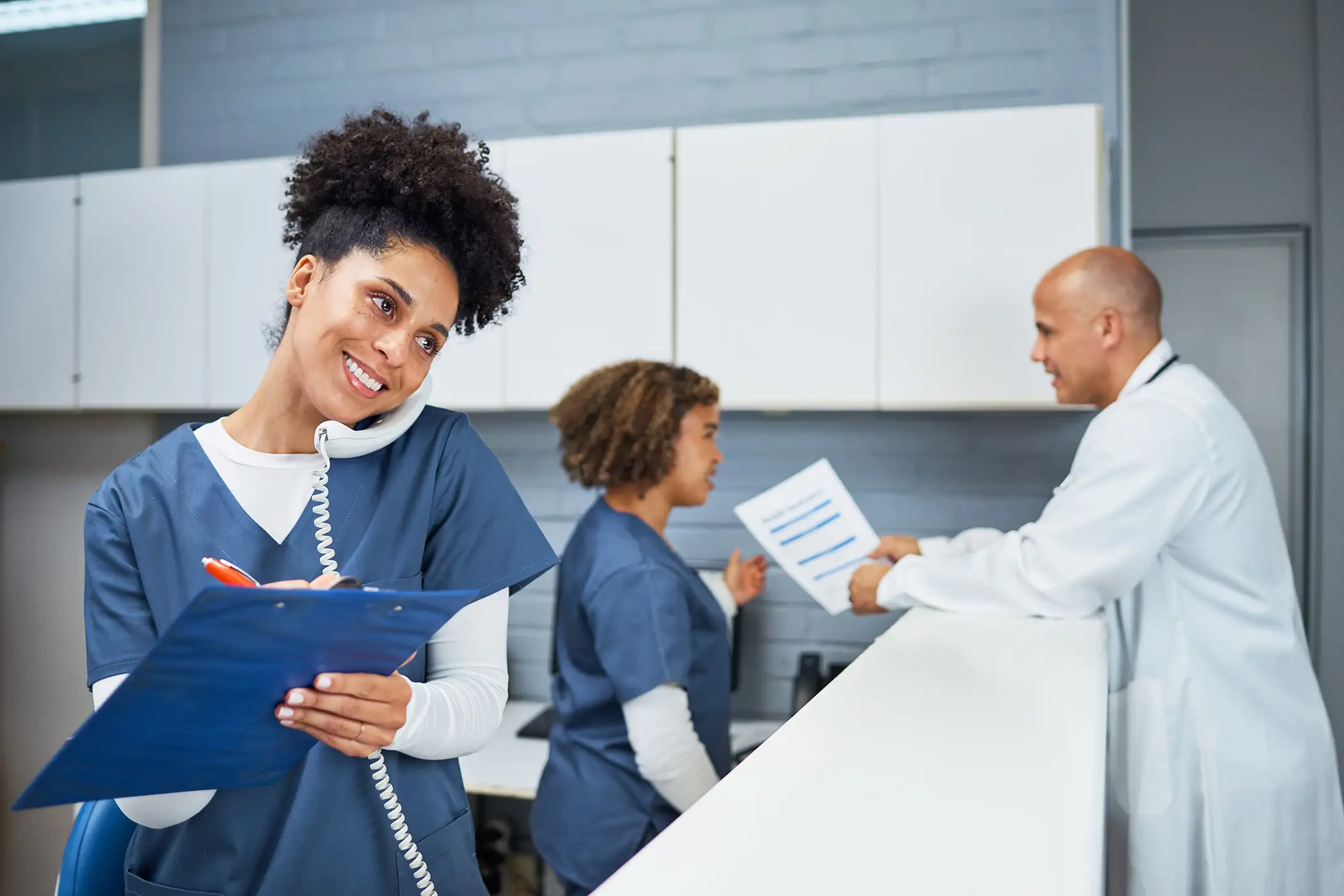 AdobeStock_1288174818 copy Medical Team Reviewing Documents and Assisting Patients in a Well-Organized Modern Clinic